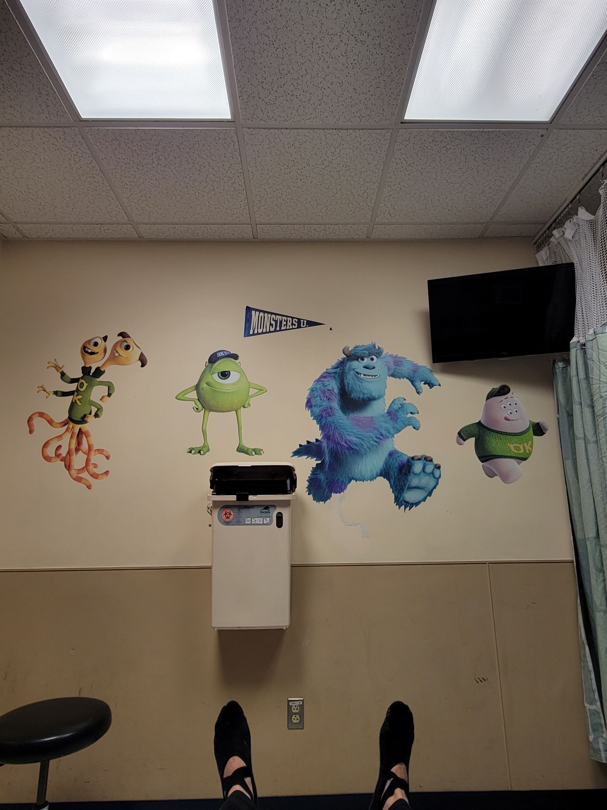 Monsters Inc characters in a hospital room with a TV and a Sharps Container